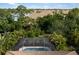 Aerial view of a screened-in pool surrounded by lush tropical landscaping and a tranquil lake in the background at 12261 Stuart Dr, Venice, FL 34293