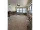 An unfinished living room featuring bright windows and a ceiling fan awaiting remodeling at 13434 1St St E, Madeira Beach, FL 33708