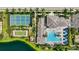 Gorgeous aerial view of community pool, clubhouse, and tennis courts surrounded by lush landscaping and mature palm trees at 13513 Deep Blue Pl, Bradenton, FL 34211