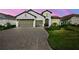 Charming home showcasing a paver driveway, a two-car garage, and lush landscaping at 13513 Deep Blue Pl, Bradenton, FL 34211