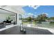 A modern balcony featuring glass railings and a dining area, overlooking a serene landscape and open to the main bedroom at 1610 N Lodge Dr, Sarasota, FL 34239
