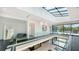 Sunlit hallway with glass railings overlooking the lower floor and a stunning glass ceiling with open views of blue sky at 1610 N Lodge Dr, Sarasota, FL 34239