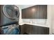 Laundry room with modern stacked washer and dryer and sleek countertop with storage cabinets at 1610 N Lodge Dr, Sarasota, FL 34239