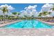 Large, luxurious swimming pool with many lounge chairs, umbrellas, and scenic palm tree landscaping at 16231 Tradewind Ter, Bradenton, FL 34211