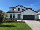 Charming two-story home boasts a well-manicured lawn, paver driveway, and stylish architectural details against a clear blue sky at 17134 Savory Mist Cir, Bradenton, FL 34211