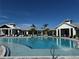 Resort-style community pool with comfortable lounge chairs, palm trees, and well-maintained buildings under a clear blue sky at 17134 Savory Mist Cir, Bradenton, FL 34211
