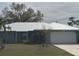 Charming single-story home with a lush lawn, a metal roof, mature landscaping, and an attached garage at 22321 Yonkers Ave, Port Charlotte, FL 33952