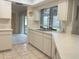 Kitchen features white cabinets, tile flooring, and a window view to outside at 22321 Yonkers Ave, Port Charlotte, FL 33952