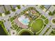 Overhead view of community pool, playground, green space, and surrounding neighborhood with parked cars and roundabout at 226 Tapa Parish Run, Bradenton, FL 34212