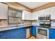 Bright kitchen featuring stainless steel appliances, granite countertops, and blue cabinets at 2315 Riverwood Pines Dr, Sarasota, FL 34231