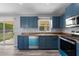 Modern kitchen with blue cabinets, stainless steel appliances, and a window overlooking the backyard at 2405 Mistleto Ln, North Port, FL 34286