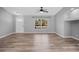 Bright living room with wood-look flooring, a ceiling fan, and a large window offering natural light at 2405 Mistleto Ln, North Port, FL 34286