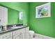 Green bathroom featuring a vanity with granite countertops, modern fixtures, and natural light at 4105 37Th E St, Bradenton, FL 34208