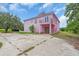 A pink two-story home with a unique roof design, concrete driveway, front balcony and landscaped yard at 4105 37Th E St, Bradenton, FL 34208