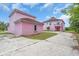 View of the pink home, garage, concrete driveway, and unique roof design in landscaped front yard at 4105 37Th E St, Bradenton, FL 34208