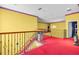 Spacious yellow hallway with a wood railing and red carpet, leading to other rooms at 4105 37Th E St, Bradenton, FL 34208