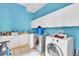 Bright laundry room with blue walls, white cabinets, washer, dryer, and a sink with ample countertop space at 4105 37Th E St, Bradenton, FL 34208