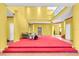 An open concept yellow living room with red carpeted stage, tiled floors, high ceilings and a partial view of the loft at 4105 37Th E St, Bradenton, FL 34208