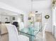 Bright dining room featuring a glass table, plush white chairs, and open access to the living room and kitchen at 4203 Schwalbe Dr # 115, Sarasota, FL 34235