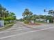 Community entrance with mature landscaping, palm trees, and a community sign under a clear, blue sky at 4203 Schwalbe Dr # 115, Sarasota, FL 34235