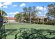 Wide view of a tennis court surrounded by trees under a bright sky at 4411 46Th W Ave # 201, Bradenton, FL 34210