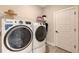 Modern laundry room featuring front-load washer and dryer units, storage shelves, and a utility sink at 491 Daylily Blvd, Nokomis, FL 34275