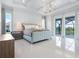 Bright main bedroom with a luxurious bed, chandelier, and access to a private balcony at 5630 Inspiration Ter, Bradenton, FL 34210