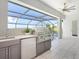 Outdoor kitchen under screened enclosure, featuring a built-in grill, sink, and mini-fridge for entertaining at 5630 Inspiration Ter, Bradenton, FL 34210