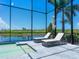 Screened-in pool area with lake view, sun loungers, and outdoor seating under palm trees at 5630 Inspiration Ter, Bradenton, FL 34210