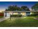 Dusk view of a single-story home features a well-manicured lawn, and a sunny yellow front door at 5685 36Th N Ave, St Petersburg, FL 33710