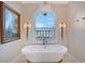 Elegant bathroom featuring a soaking tub beneath a stunning arched window with water view at 571 Birdie Ln, Longboat Key, FL 34228