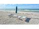 Beach chairs and umbrella set up in the sand on a sunny day by the ocean at 571 Birdie Ln, Longboat Key, FL 34228