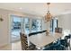 Elegant dining room with a modern chandelier, stylish zebra-print chairs, and sliding glass doors overlooking the waterfront at 571 Birdie Ln, Longboat Key, FL 34228