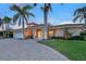 Stunning exterior with a paver driveway and lush landscaping with palm trees lining the entrance of this beautiful home at 571 Birdie Ln, Longboat Key, FL 34228