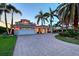 Beautiful home with a paver driveway, lush landscaping, and a spacious garage, all framed by mature palm trees at 571 Birdie Ln, Longboat Key, FL 34228