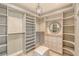 Spacious walk-in closet featuring custom shelving, drawers, a mirror, and a stylish ottoman at 571 Birdie Ln, Longboat Key, FL 34228