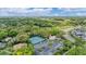 A serene aerial view showcases the community tennis courts surrounded by lush greenery and mature trees at 5803 Garden Lakes Palm, Bradenton, FL 34203