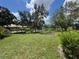 Scenic backyard featuring a pond, a wooden dock, lush green grass, and mature trees under a partly cloudy sky at 5803 Garden Lakes Palm, Bradenton, FL 34203