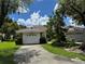 Charming home with a tile roof, lush landscaping, and a concrete driveway leading to a two-car garage at 5803 Garden Lakes Palm, Bradenton, FL 34203