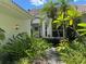 Inviting front entrance with tropical plants, stucco walls, and a white framed archway leading to the front door at 5803 Garden Lakes Palm, Bradenton, FL 34203