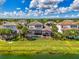 An aerial view showcasing a home with a screened-in pool, tropical landscaping, and a serene backyard overlooking a lake at 6318 Rivo Lakes Blvd, Sarasota, FL 34241