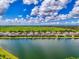 An aerial view reveals a serene lakefront community under a bright blue sky with fluffy white clouds and lush green surroundings at 6318 Rivo Lakes Blvd, Sarasota, FL 34241