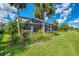 Lush backyard featuring a screened-in pool area, vibrant tropical landscaping, and a well-manicured lawn at 6318 Rivo Lakes Blvd, Sarasota, FL 34241