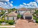 Beautiful two-story home featuring lush landscaping, a brick driveway, and a two-car garage at 6318 Rivo Lakes Blvd, Sarasota, FL 34241