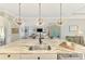Open kitchen features white cabinets, modern pendant lights, bar stool seating, and a view into the living area at 6318 Rivo Lakes Blvd, Sarasota, FL 34241