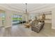Bright living room boasts a modern chandelier, gray sofa and a view of the pool and lake at 6318 Rivo Lakes Blvd, Sarasota, FL 34241