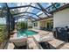 Spacious screened-in pool area with lounge chairs, outdoor kitchen, and peaceful lake views at 6318 Rivo Lakes Blvd, Sarasota, FL 34241