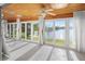 Bright sunroom with tile floors, wood ceiling, and large windows showcasing a serene lake view at 655 Spanish Way, Longboat Key, FL 34228