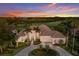 Beautiful home at sunset with mature palms, manicured landscaping, and a serene golf course view at 7144 Ashland Gln, Lakewood Ranch, FL 34202