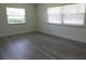 Well-lit bedroom with gray wood-look flooring and two windows, offering ample natural light at 7157 Fairway Bend Cir, Sarasota, FL 34243
